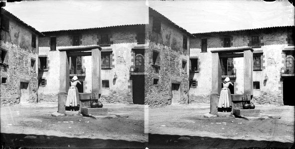Una dona traient aigua d'un pou a pla plaça de Sant Julià de Vilatorta