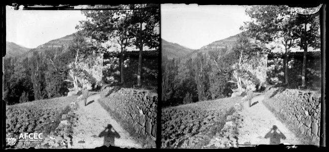 Un home en un camí al costat d'un camp i al fons la masia de Roques Blanques