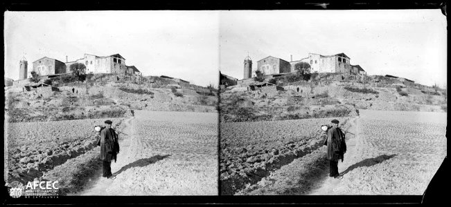 Un home entre camps de conreu i al fons el poble de Su