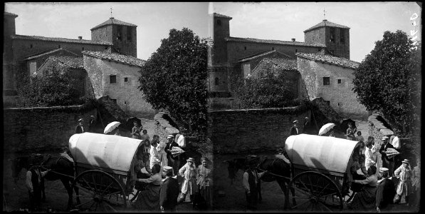 Una tartana amb gent voltant i al fons l'església de Vilalleons