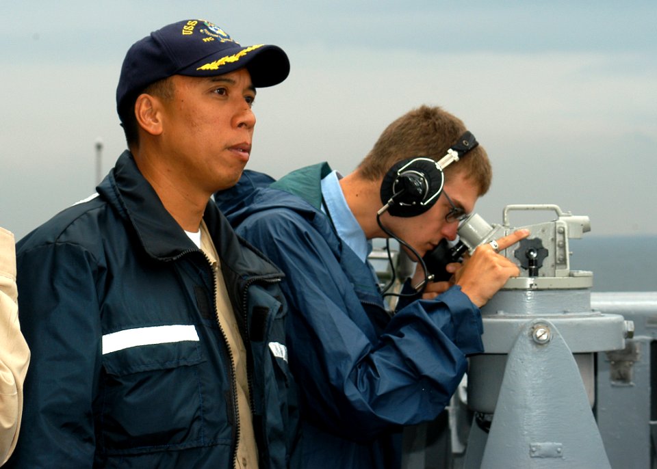 US Navy 060901-N-2716P-027 USS Gary (FFG 51) Commanding Officer, Cmdr. Joseph Deleon, looks out from the bridge wing as Quartermaster Seaman Michael Lind takes a bearing reading