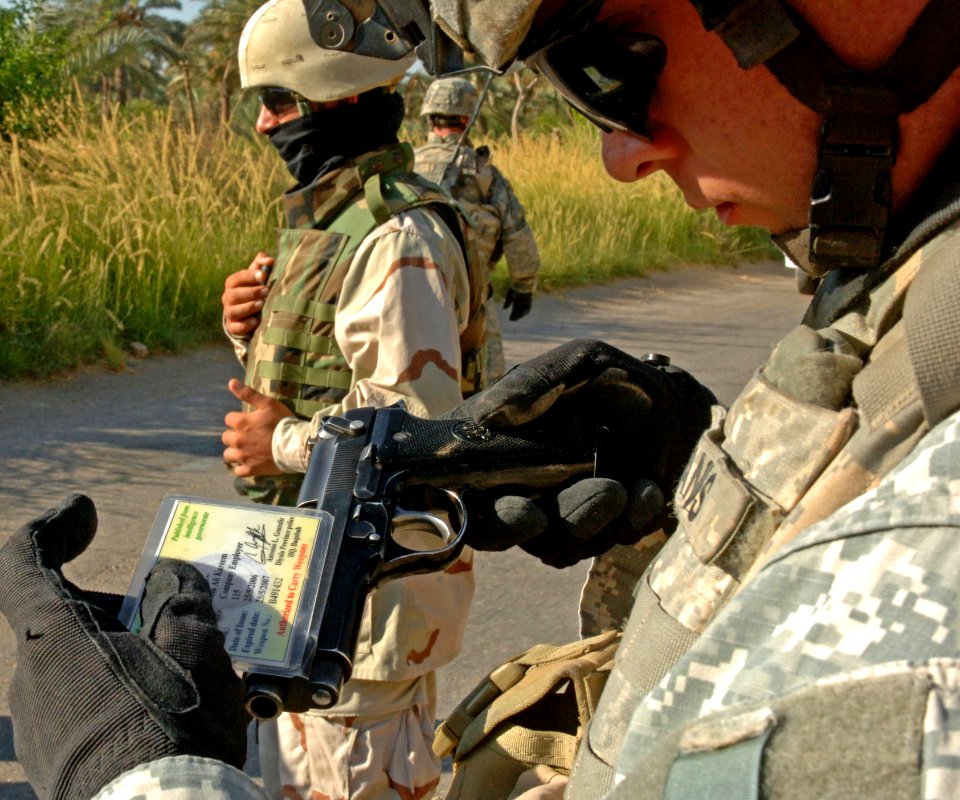 US Navy 060915-N-4097B-004 U.S. Army Sgt. Jeremy Wallis inspects the owner's card of a gun found during a routine search near Baqubah, Iraq