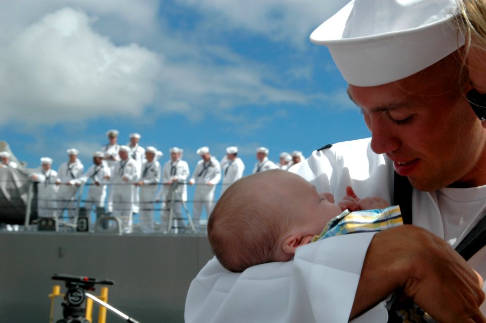 US Navy 060905-N-4965F-008 A new father holds his child for the first time after returning from a six-month deployment aboard the guided missile destroyer USS Russell (DDG 59)