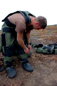US Navy 060830-N-9195K-027 Explosive Ordinance Disposalman 2nd Class Thayer Jones, assigned to Naval Special Clearance Team One (NSCT-1), suits himself up into a special suit used for explosive disposal, while participating in
