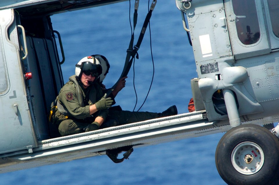 US Navy 060908-N-8604L-583 An MH-60S Air Crewman from Helicopter Sea Combat Support Squadron Two Five (HCS-25) gives hand signals to an aircraft director during a vertical replenishment between USS Kitty Hawk (CV 63)