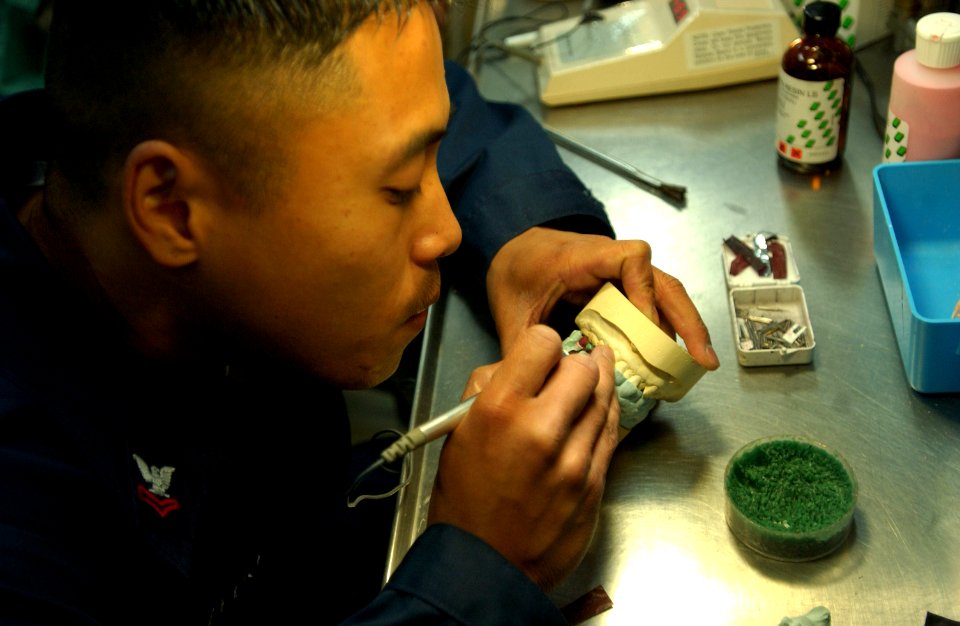 US Navy 061024-N-4133B-061 Hospital Corpsman 2nd Class Noel Toledo from San Diego applies wax to a mold of a mouth in the dental office aboard USS Ronald Reagan (CVN 76)