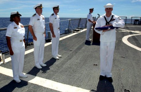 US Navy 060908-N-9851B-004 Gunner's Mate 2nd Class Robert Prine presents an American Flag to USS Hopper (DDG 70) Commanding Officer, Cmdr. Peter Driscoll during a burial-at-sea for retired Chief Warrant Officer Charles Paris photo