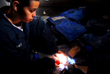 US Navy 061024-N-4776G-148 Seaman Angie Jimenez from Queens, N.Y., illuminates a strobe flashlight while conducting float coat maintenance aboard USS Ronald Reagan (CVN 76)