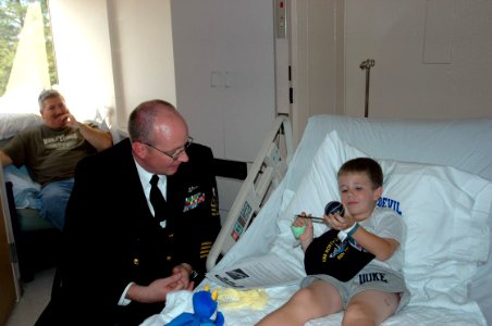 US Navy 061018-N-5531C-002 A chief petty officer assigned to the Virginia-class fast-attack submarine North Carolina (SSN 777) gives a ball cap to a child at Duke Children's Hospital