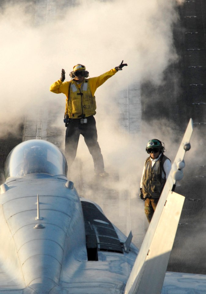 US Navy 061023-N-4776G-205 An aviation boatswain's mate (handler) directs an F-A-18 Hornet into its launch position during flight operations on the flight deck aboard the Nimitz-class aircraft carrier USS Ronald Reagan (CVN 76)