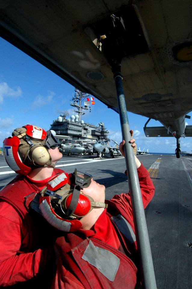 US Navy 061023-N-1332Y-200 Aviation Ordnanceman Airman Britt Mitchell (left) and Aviation Ordnanceman Brandon Little connect a cargo pendant to a hovering MH-60S Seahawk on the flight deck aboard USS Kitty Hawk (CV 63)