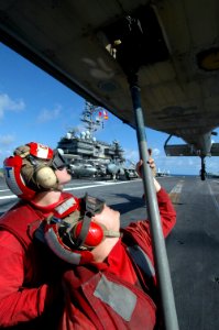 US Navy 061023-N-1332Y-200 Aviation Ordnanceman Airman Britt Mitchell (left) and Aviation Ordnanceman Brandon Little connect a cargo pendant to a hovering MH-60S Seahawk on the flight deck aboard USS Kitty Hawk (CV 63)