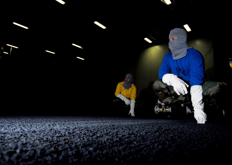 US Navy 061104-N-3729H-107 Sailors simulate bracing for shock during a general quarters drill in the hangar bay