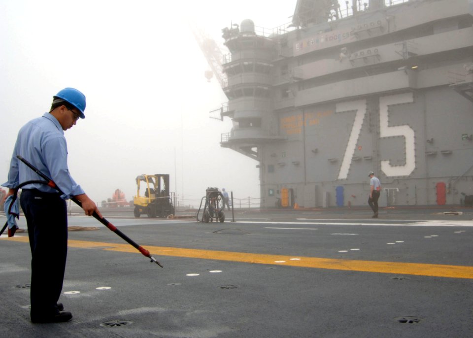 US Navy 061019-N-7405P-001 Aviation Boatswain's Mate (Handler) Airman David Rivera uses a low-pressure air hose to clean padeyes on the flight deck aboard USS Harry S. Truman (CVN 75)