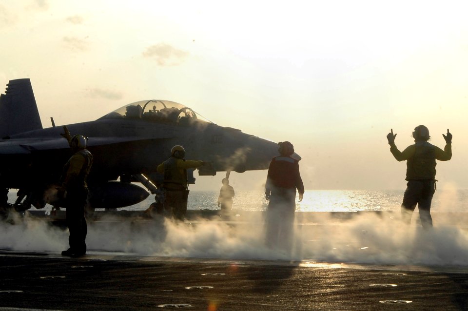 US Navy 061024-N-6106R-056 Aircraft directors signal an F-A-18F Super Hornet assigned to Strike Fighter Squadron One Zero Two (VFA-102), onto catapult three in preparation for evening flight operations