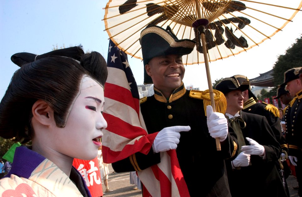 US Navy 061103-N-9851B-003 Master-at-Arms 1st Class Marcus Watkins, dressed as a member of Commodore Matthew C. Perry's crew, holds a Japanese kasa as he talks with Japanese participants of the Tokyo