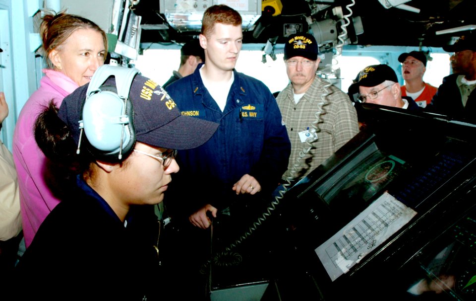 US Navy 061026-N-0890S-098 Seaman Stephanie Inge mans the helm of the guided-missile cruiser USS Mobile Bay (CG 53) while Ensign Mathew P. Johnson and Leaders to Sea participants observe