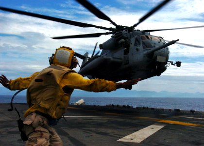 US Navy 061028-N-5067K-013 USS Essex (LHD 2) landing signal enlisted (LSE), Aviation Boatswain's Mate Airman Sendy Jolicoeur, guides in a CH-53E Super Stallion loaded with Marines and equipment assigned to Marine Medium Helicop