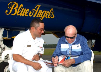US Navy 061027-N-1810F-039 Raleigh Dusty Rhodes, one of the first pilots and commanders of the Blue Angels, autographs a poster for Mass Communication Specialist 2nd Class Joseph Olivares before the practice air show aboard Nav
