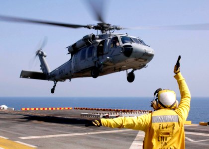 US Navy 061028-N-8547M-007 Aviation Boatswain's Mate Airman Dukins Admettre signals to an MH-60S Seahawk helicopter to land on the flight deck of amphibious assault ship USS Saipan (LHA 2)