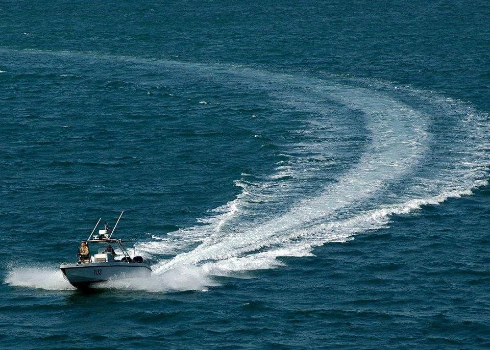US Navy 061110-N-8547M-046 A harbor patrol boat unit assigned to Naval Security Force Bahrain escorts amphibious assault ship USS Saipan (LHA 2) away from the pier following a brief port visit and offload of mine sweeping equip