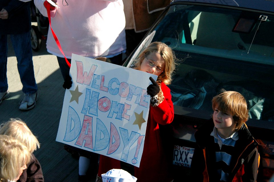 US Navy 061106-N-4515N-125 The daughter of a Sailor holds a sign welcoming her father back during the homecoming ceremony for the guided-missile destroyer USS Ross (DDG 71)