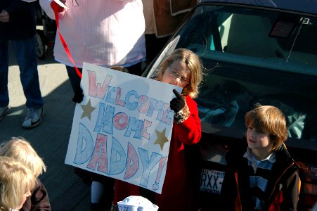 US Navy 061106-N-4515N-125 The daughter of a Sailor holds a sign welcoming her father back during the homecoming ceremony for the guided-missile destroyer USS Ross (DDG 71)