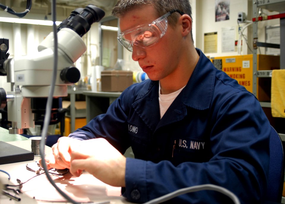 US Navy 061106-N-2636M-020 U.S. Navy Aviation Electrician Airman Bryan Long conducts cable repairs on an AC adaptor aboard the amphibious assault ship USS Bataan (LHD 5)