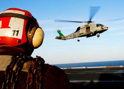 US Navy 061110-N-3729H-234 A line division Sailor stands ready with chock and chains to secure an SH-60F Seahawk assigned to Helicopter Anti-Submarine Squadron Eight (HS-8) as it lands on the flight deck