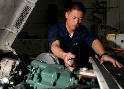 US Navy 061104-N-2659P-050 Aviation Support System Technician Airman Apprentice Joseph Ferradino performs routine daily maintenance on a tow tractor in the hangar bay