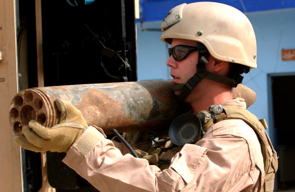 US Navy 061030-F-7426P-311 U.S. Navy Explosive Ordnance Technician 1st Class Donnie Walkey, assigned to Explosive Ordnance Disposal Mobile Unit Three (EODMU-3), carries a 107 mm rocket out of the Iraqi police headquarters in Ad
