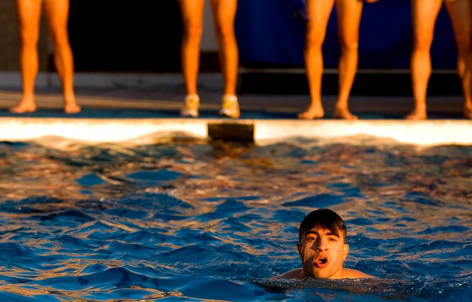 US Navy 061107-N-9769P-522 Naval Diving and Salvage Training Center students stand at the end of the pool and motivate Ensign Matthew Horry as he swims against the clock while taking the physical fitness test