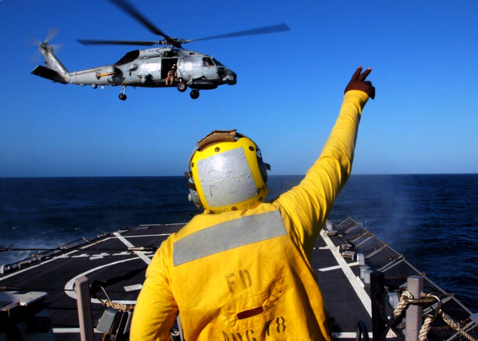 US Navy 071006-N-4014G-393 oatswain's Mate 3rd Class Emanuel Williams waves off an SH-60 Seahawk attached to guided-missile destroyer USS Porter (DDG 78) from the ship's flight deck