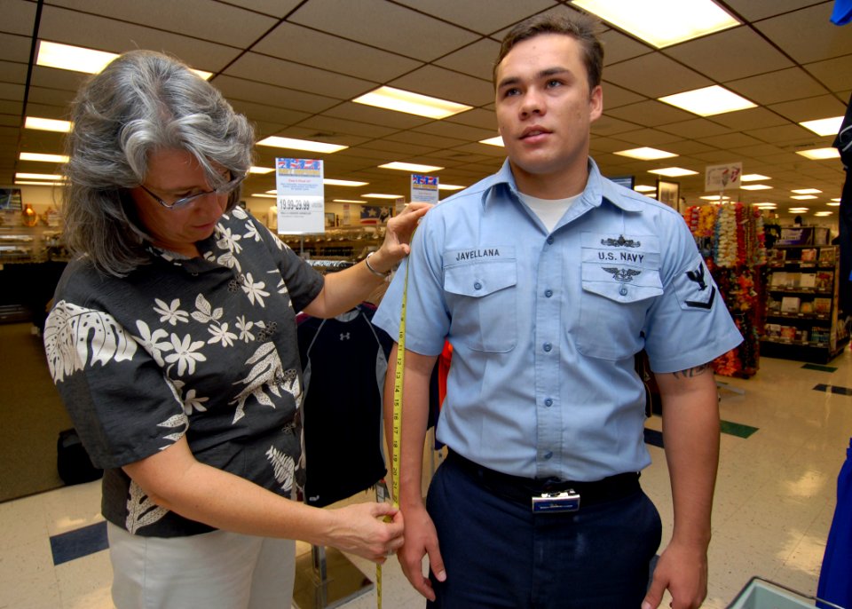 US Navy 071003-N-9758L-050 Donna Zlotnick, senior clothing designer and Task Force Uniform team lead at the Navy Clothing and Textile Research Facility, measures the right arm of Yeoman 3rd Class Brandon Javellana, assigned to