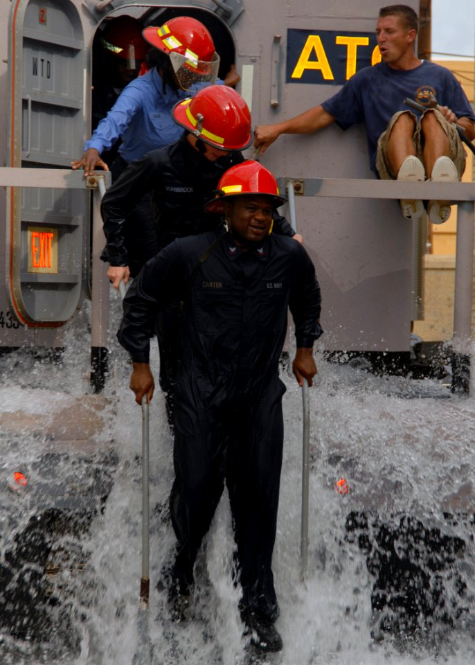 US Navy 071004-N-8544C-005 Sailors assigned to Precommissioning Unit (PCU) George H. W. Bush (CVN 77) exit the mobile damage control trainer after participating in training on pipe patching, plugging and dewatering