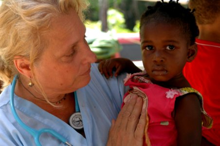 US Navy 071005-N-7088A-130 Genie Lindsey, a Project Hope registered nurse attached to Military Sealift Command hospital ship USNS Comfort (T-AH 20), holds a little girl visiting the Onverwacht Clinic photo