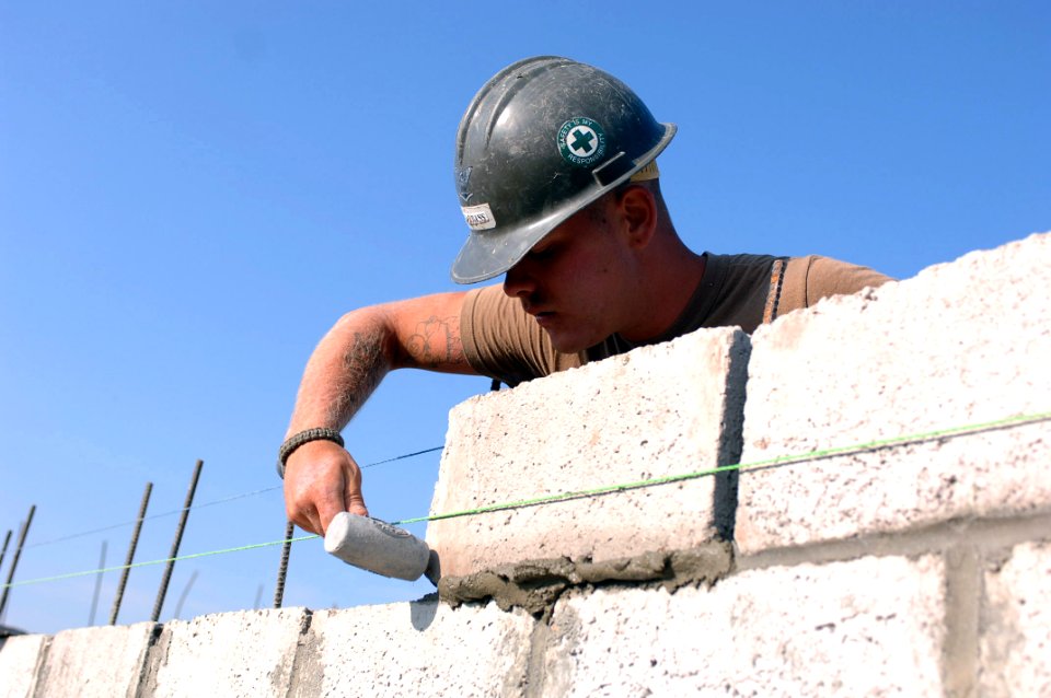 US Navy 071006-N-1003P-002 Builder 3rd Class Karl Rabbass, assigned to Naval Mobile Construction Battalion (NMCB) 40, Det. Horn of Africa (HOA), uses a mallet to make sure the cement block fits securely