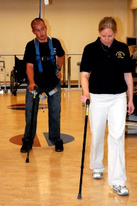 US Navy 071015-N-5086M-202 Retired Marine Corps Cpl. Timothy Jeffers walks on his prosthetic legs while using the hands-free harness walking gait training device during a therapy session in the new Comprehensive Combat and Com