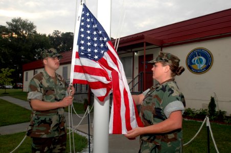 US Navy 071010-N-2456S-090 Information Systems Technician Seaman Bradley Encinas and Personnel Specialist 1st Class Carrie Singleton prepare to raise a flag flown over Iraq and Afghanistan during the one-year anniversary for Ex photo