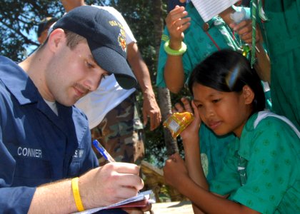 US Navy 071016-N-6710M-089 Fireman Farrell W. Conner gives an autograph to a student of Gordon Heights Elementary School while conducting a community relations project in the Republic of Philippines