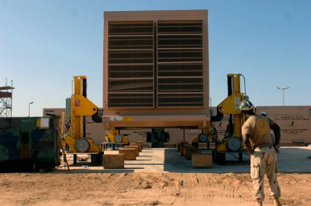 US Navy 071018-N-1003P-034 Construction Mechanic 1st Class Alfredo Ozuna, the lead mechanic attached to Mobile Utilities Support Equipment looks on as a generator container is lowered onto a concrete pad