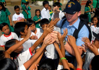 US Navy 071016-N-6710M-004 Information Systems Technician Seaman Drew T. Spaeth hands out candy to the students of Gordon Heights Elementary School while conducting a community relations project in the Republic of Philippines