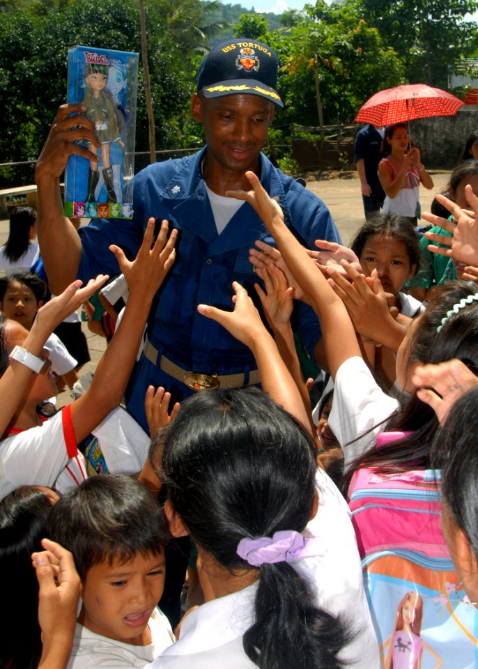 US Navy 071016-N-6710M-118 Cmdr. Todd A. Lewis, commanding officer of the USS Tortuga (LSD 46), hands out toys to the students of Gordon Heights Elementary School while conducting a community relations project in the Republic o