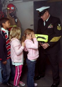 US Navy 071019-N-0483B-006 Chief Damage Controlman Ted Leavitt shows a group of children how a Naval Firefighting Thermal Imager (NFTI) works during a Friends and Family Day Cruise