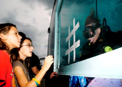 US Navy 071021-N-5208T-001 A member of the Explosive Ordnance Disposal Mobile Unit (EODMU) 2, plays underwater tic-tac-toe with participants at the North Carolina State Fair while submerged in a Dive Tank