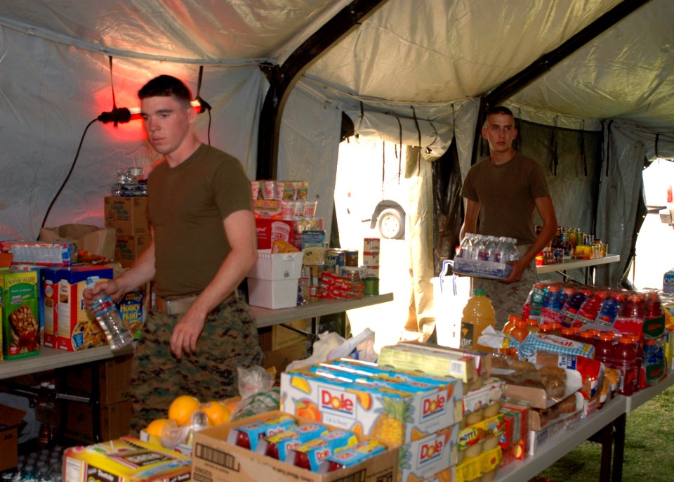 US Navy 071023-N-4973M-019 Marine Pfc. Jared B. Davis and Lance Cpl. Orion S. Pease, assigned to the 24 Fox Company, carry supplies into tents intended for wildfire evacuees on Turner Field at Naval Amphibious Base Coronado