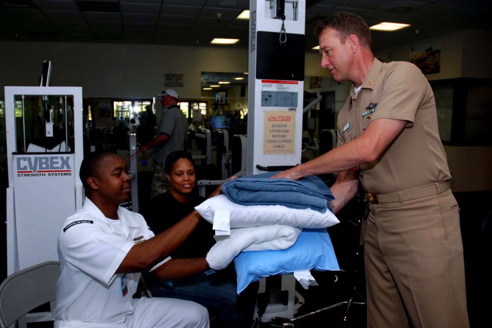 US Navy 071023-N-5086M-004 Senior Chief Hospital Corpsman Trevor Dallas-Orr hands blankets and pillows to Personnel Specialist 1st Class William Clincy and his wife for their stay at the temporary evacuation site on base