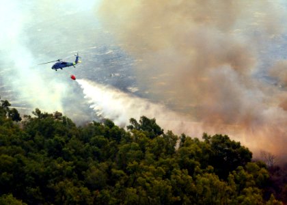 US Navy 071023-N-3069F-005 An MH-60S Seahawk assigned to Helicopter Sea Combat Squadron (HSC) 85, dumps water from a full 420-gallon extinguishing trough onto of one of the many areas in San Diego County suffering from an ongoi