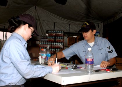 US Navy 071023-N-4973M-017 Interior Communications Electrician 3rd Class Natoshia Reid and Engineman 2nd Class Shannon A. Smith account for personnel and pets evacuated to the 500-person tent camp on Turner Field at Naval Amphi photo