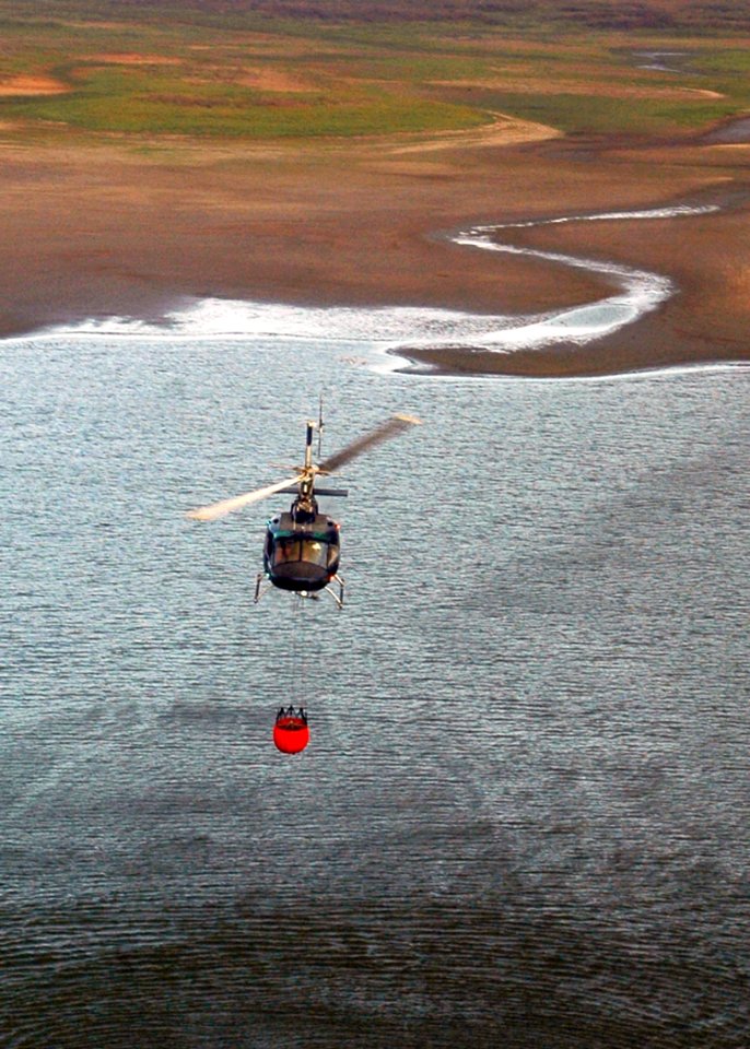 US Navy 071023-N-3069F-029 A civilian helicopter refills a bucket used to drop water in coordination with fire fighters and Navy pilots assigned to Helicopter Sea Combat Squadron (HSC) 85